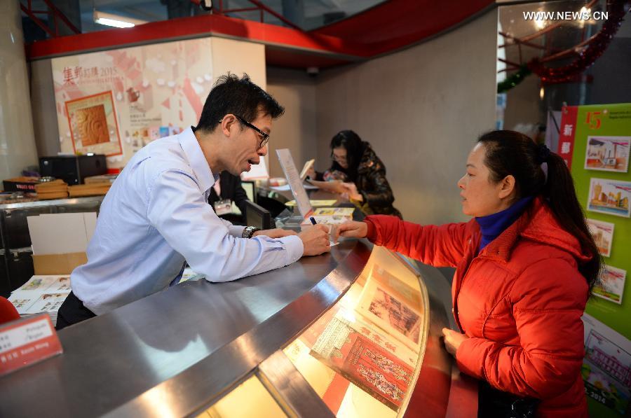 A woman purchases souvenir post stamps at a post office in Macao, south China, Dec. 20, 2014. The Macao Post issued souvenir stamp folders and two sets of philatelic items to mark the 15th anniversary of the establishment of the Macao Special Administrative Region (SAR) on Saturday. (Xinhua/Qin Qing)