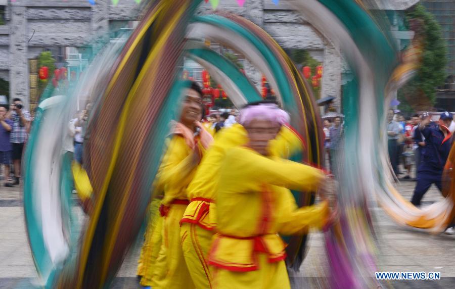 Folk artists perform a dragon dance on a street in Qianjiang City, central China's Hubei Province, June 14, 2015.