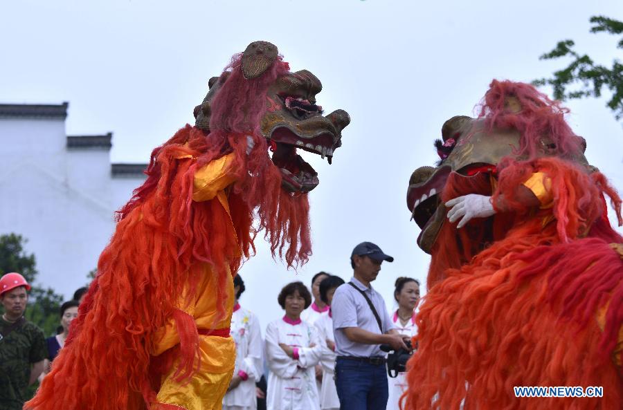 Folk artists perform a lion dance on a street in Qianjiang City, central China's Hubei Province, June 14, 2015.