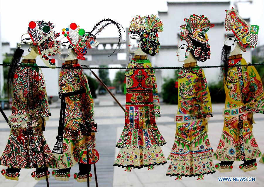 Folk artists perform shadow play on a street in Qianjiang City, central China's Hubei Province, June 14, 2015.