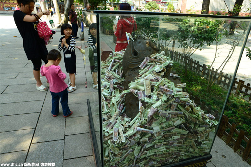 Bronze statues in Guangzhou scenic spot “swallowed” by banknotes and coins