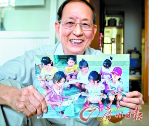 Professor Huang Qipeng holds a photo of children reading books he donated. (Photo/Guangzhou Daily)