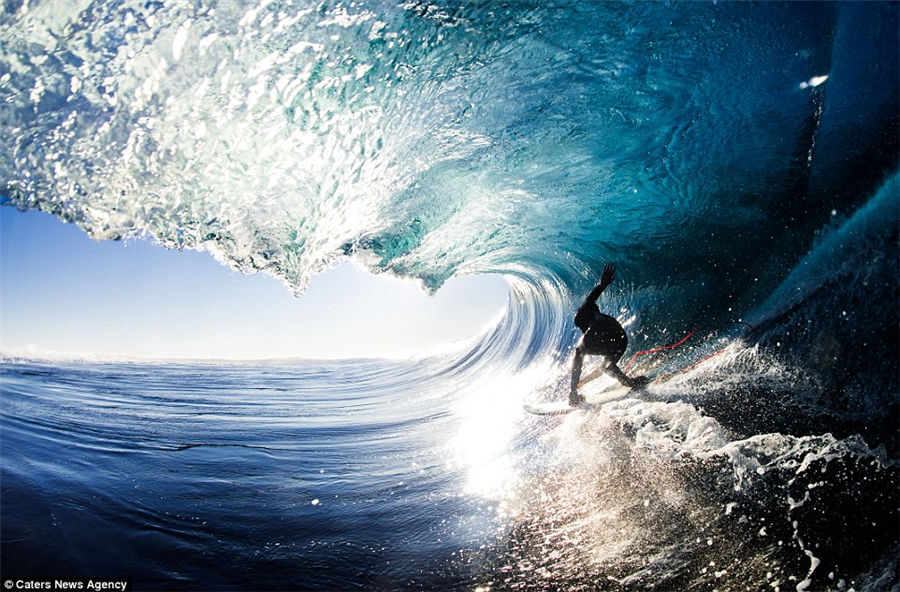 Teenager captures incredible photos of pro-surfers riding huge waves from inside the barrel as he tags along behind them
