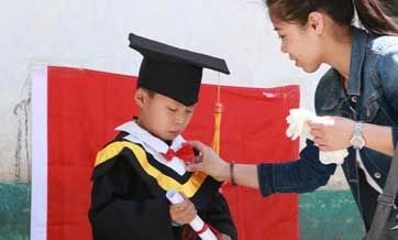 Volunteers take photos for left-behind children in bachelor gowns