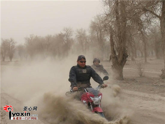 Braving dust and wind, policemen in the desert ride motorcycles to perform duty