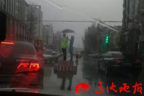 Girl holds umbrella for police officer during heavy rainstorm