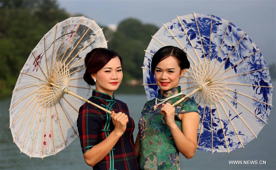 Ladies pose with umbrellas at a Qipao show by the Rongjiang river in Rong'an County, south China's Guangxi Zhuang Autonomous Region, Sept. 20, 2016. Qipao is a traditional Chinese dress. 