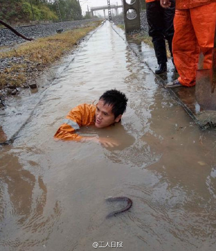Railway worker climbs into dirty water to dredge gutter