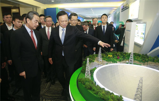 Foreign Minister Wang Yi (left front) and Secretary of Guizhou Provincial CPC Committee Chen Min'er(right front) look at a model of the radio telescope set up in Guizhou in a promotion event in Beijing on Tuesday. (Photo by Feng Yongbin/chinadaily.com.cn)