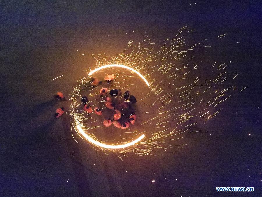 Performers spray burning iron chips to shower sparks-like fireworks