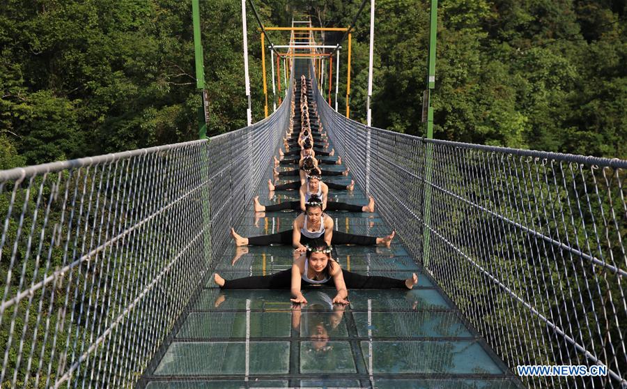 Yoga lovers practice yoga on glass bridge at Shuanglonggou forest park