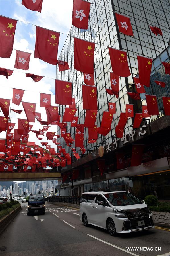 Vehicles run under Chinese national flags and flags of Hong Kong Special Administrative Region in Tsim Sha Tsui of Hong Kong, south China, June 27, 2017. July 1, 2017 marks the 20th anniversary of Hong Kong's return to the motherland. (Xinhua/Lo Ping Fai)