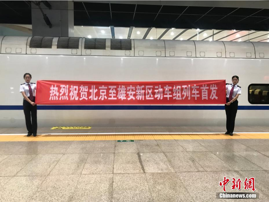 Workers lift a banner saying the first bullet train running from Beijing to Xiongan on July 6, 2017.