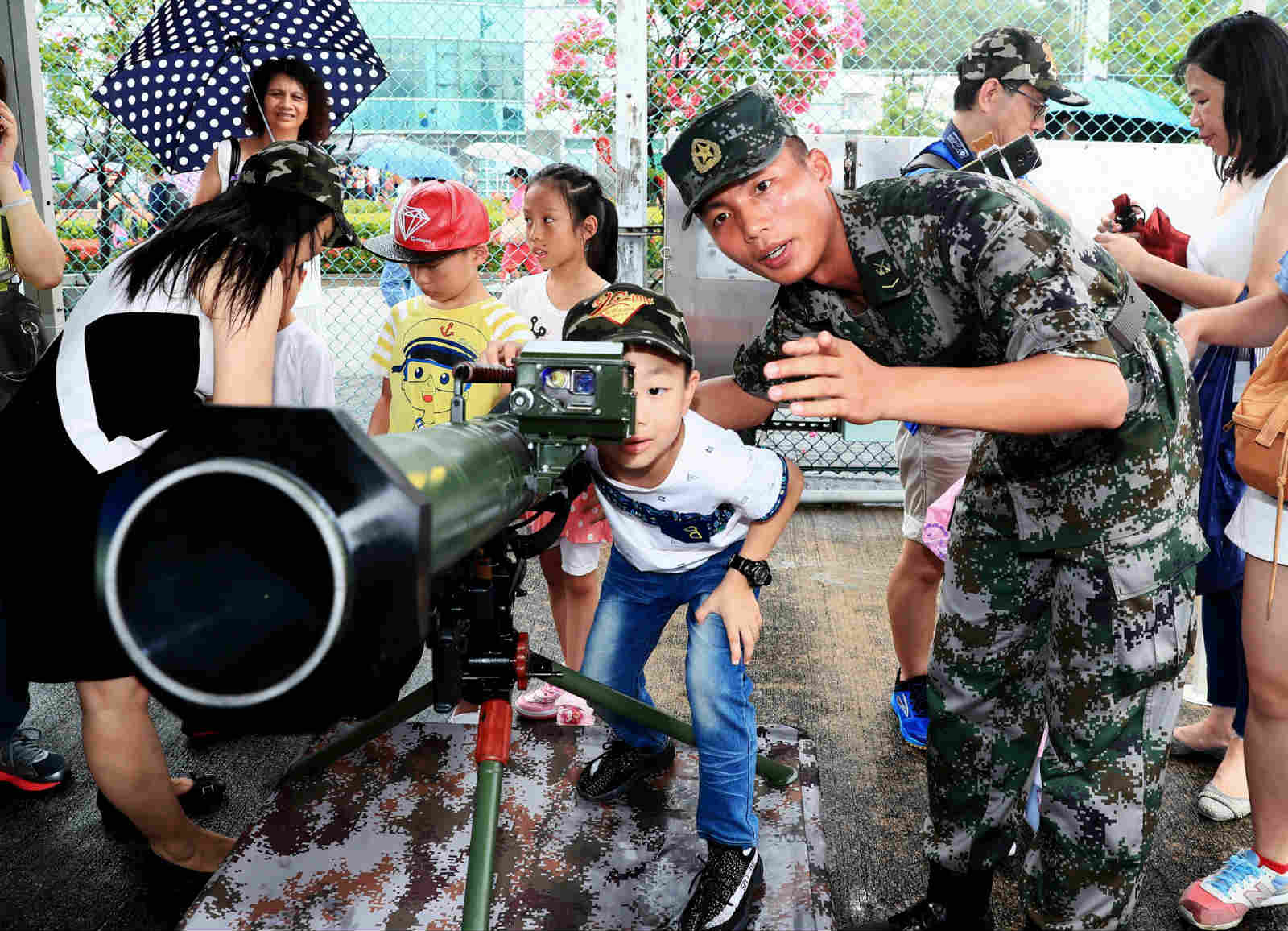 A soldier introduces the man-portable anti-tank missile system to a Hong Kong child on the camp-open day in the Ngong Shuen Chau Barracks. In order to celebrate the 20th anniversary of Hong Kong's return to the motherland, the Ngong Shuen Chau Barracks of the PLA Hong Kong Garrison held the camp-open day activities on the morning of July 8, 2017. (eng.chinamil.com.cn/Photo by Zhou Hanqing) 