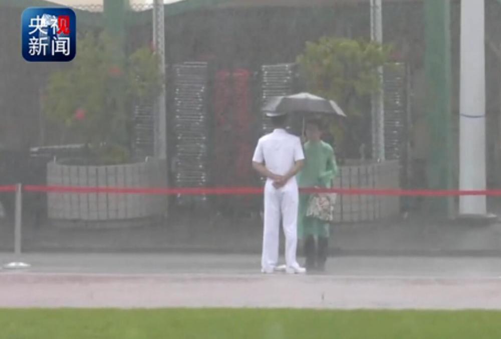 Hong Kong citizen holds umbrella for PLA guard in rainstorm