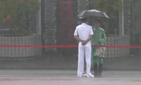 HK citizen holds umbrella for PLA guard in rainstorm
