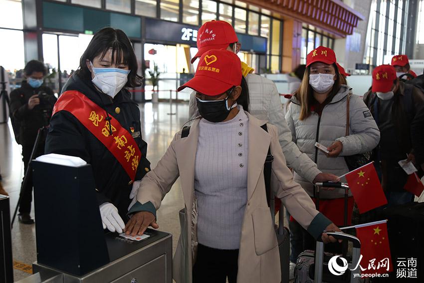 A staff member at Kunmingnan Railway Station helps migrant workers pass a checkpoint to get onto the platform of the station. (People’s Daily Online/Li Faxing)