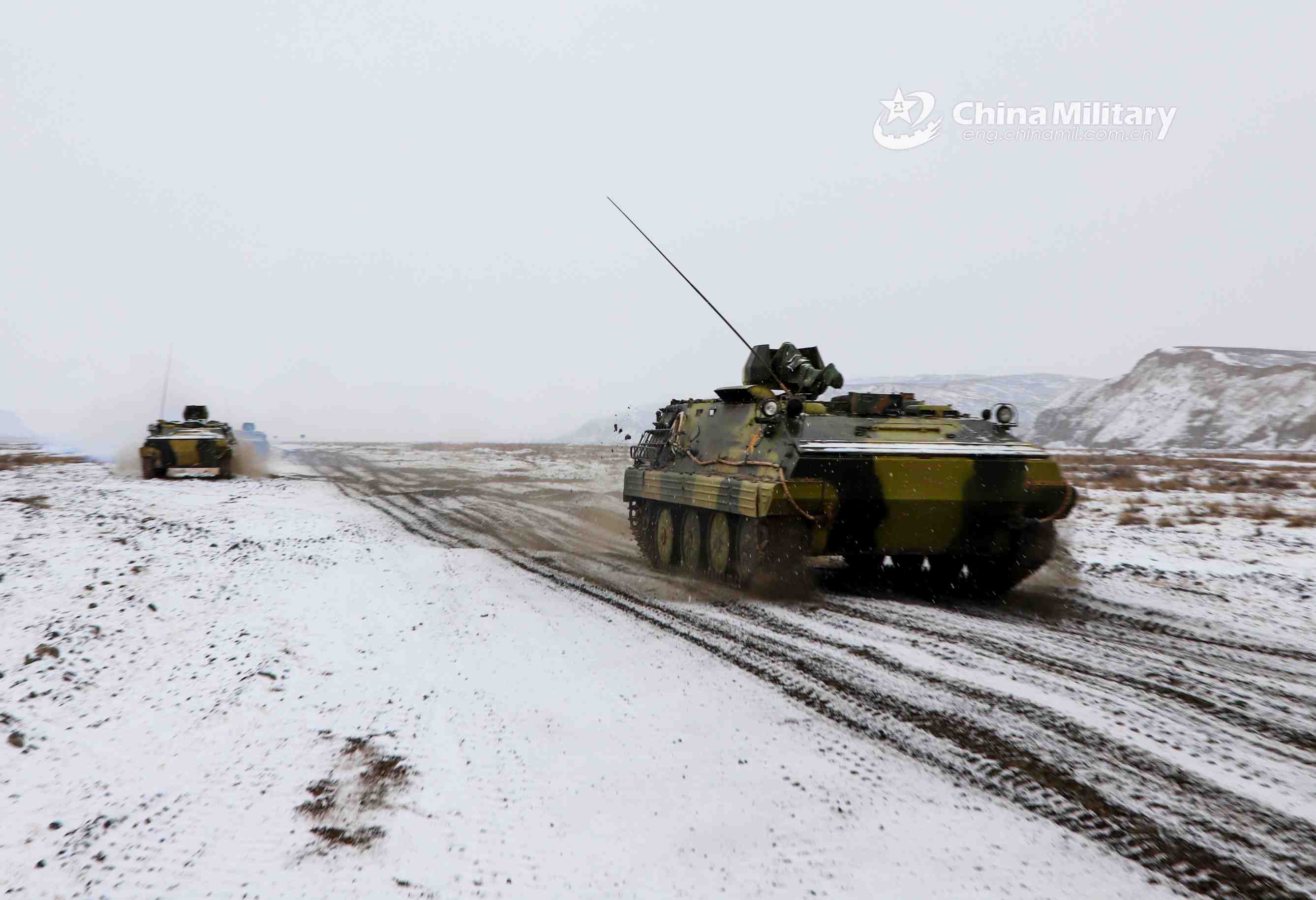 Armored vehicles rumble on snow-covered road