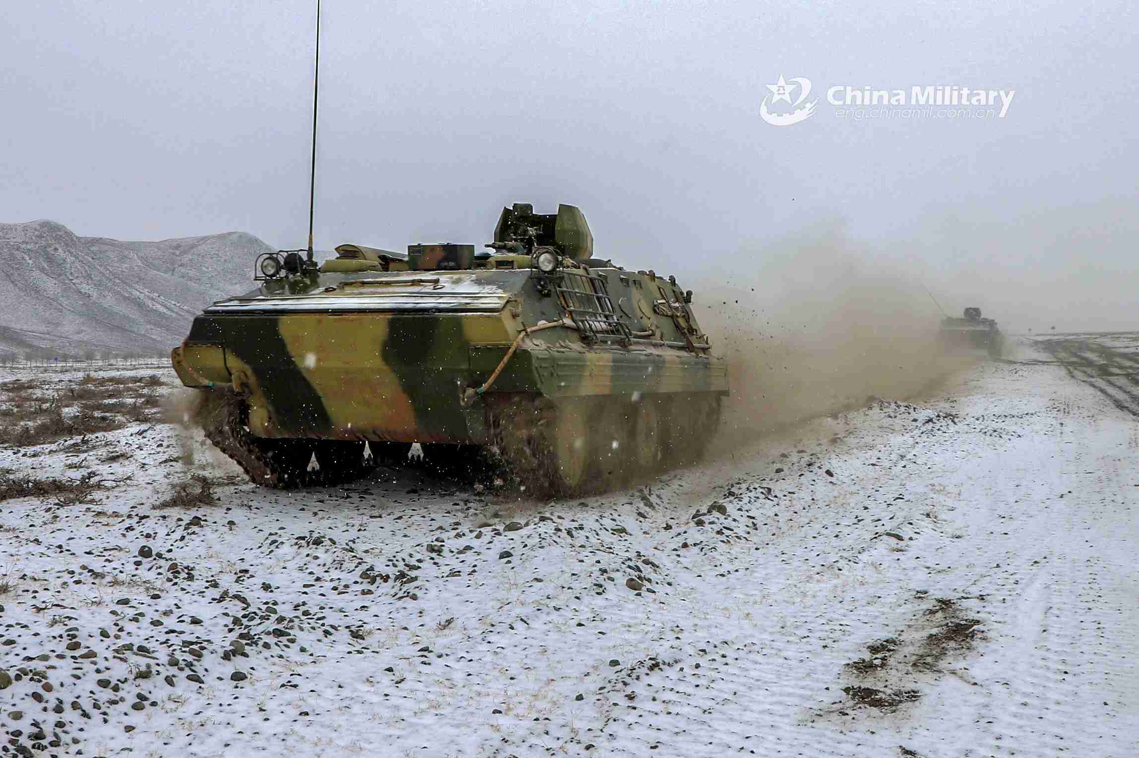 Armored vehicles rumble on snow-covered road