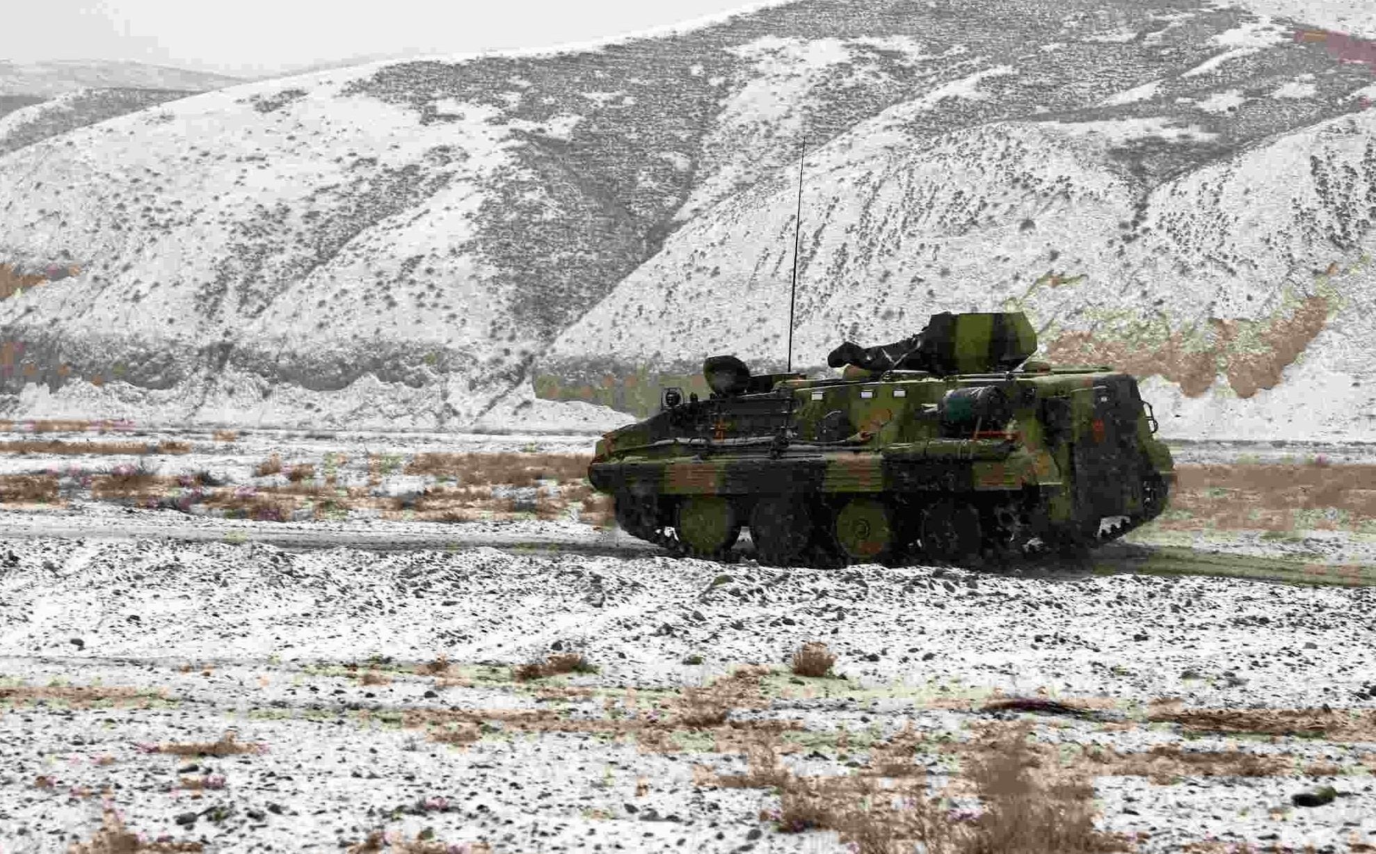 Armored vehicles rumble on snow-covered road