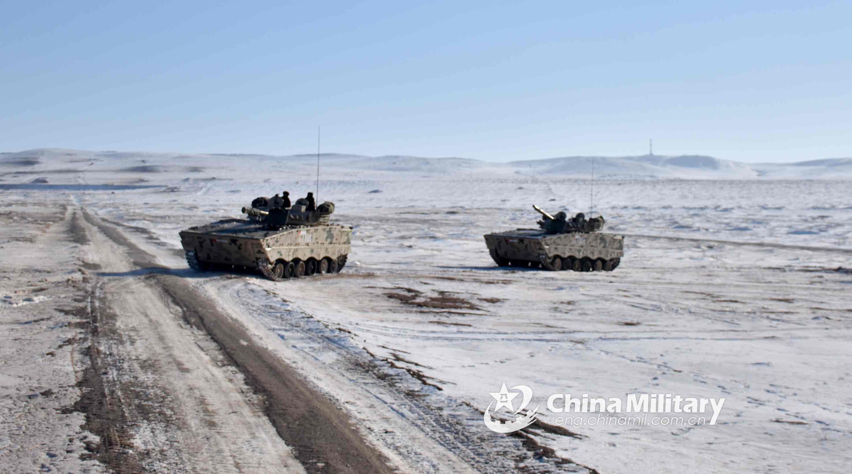 Soldiers drive armored vehicles on snow ground