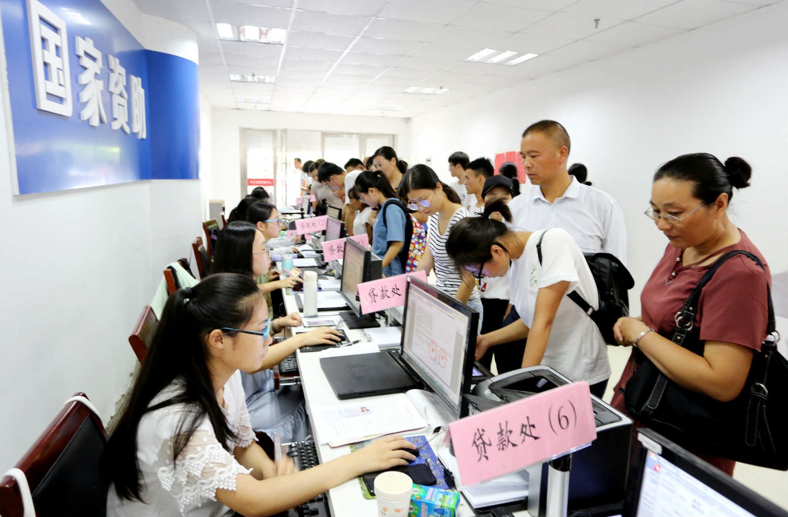College-bound students and their parents apply for student-origin-based loans at a student loan management center of Donghai County, Lianyungang, east China''s Jiangsu Province, Aug. 5, 2019. (People''s Daily Online/Zhang Kaihu)