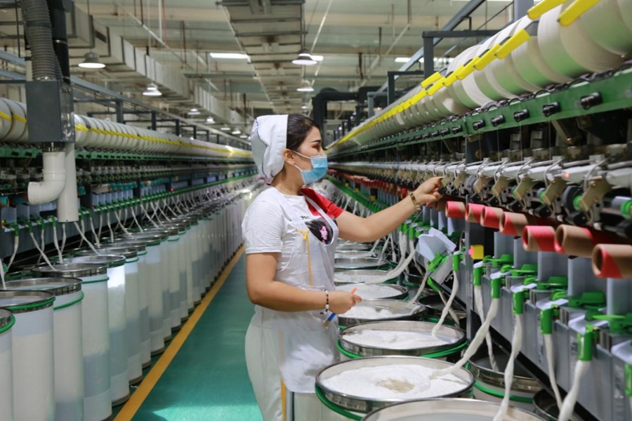 A woman works at a workshop of a textile factory in Awat county, Aksu, northwest China's Xinjiang Uygur autonomous region, July 10, 2021. The factory is preparing a 1,200-tonne order for its clients in Shandong, Jiangsu and Zhejiang provinces. (People's Daily Online/Bao Liangting)