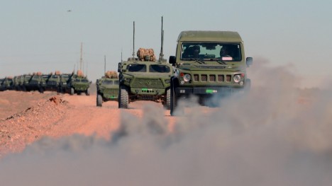 Military trucks pass through simulated infected area