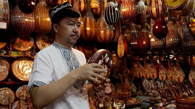 Depicting beauty of Xinjiang on a small tambourine