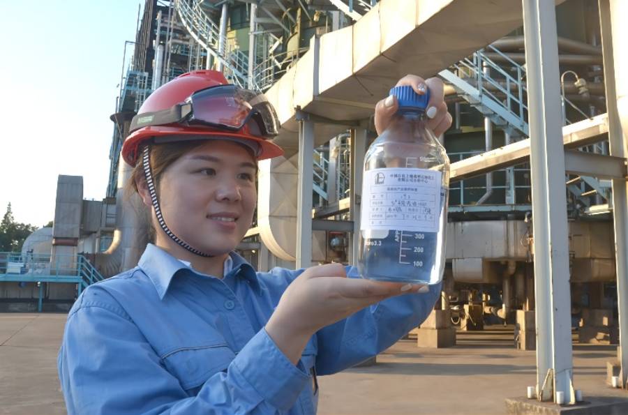A technician of the analytic center of Sinopec Shanghai Gaoqiao Petrochemical Co., Ltd., a petrochemical company affiliated to China Petrochemical Corporation (Sinopec Group), observes a bottle of gasoline product in front of a gasoline production facility. The carbon dioxide emissions created during the whole life cycle of the product are compensated for through efforts of the producer. (Photo/Courtesy of Sinopec Group)