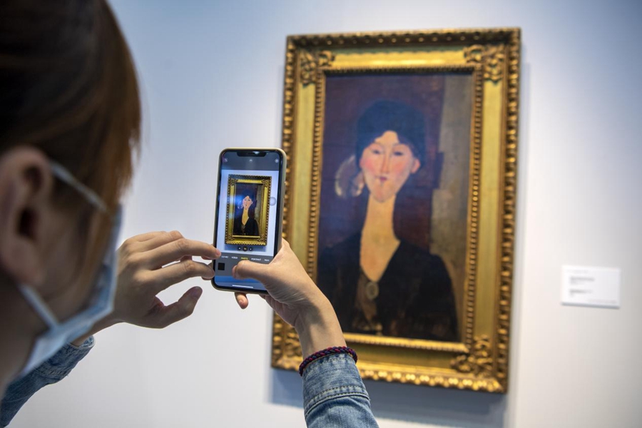 A visitor takes a photo of a painting by Italian artistic master Amedeo Modigliani at the cultural relics and art display center during the fourth China International Import Expo (CIIE) in Shanghai on Nov. 8, 2021. The last time the artwork was publicly displayed was in 1973. (People’s Daily Online/Weng Qiyu)