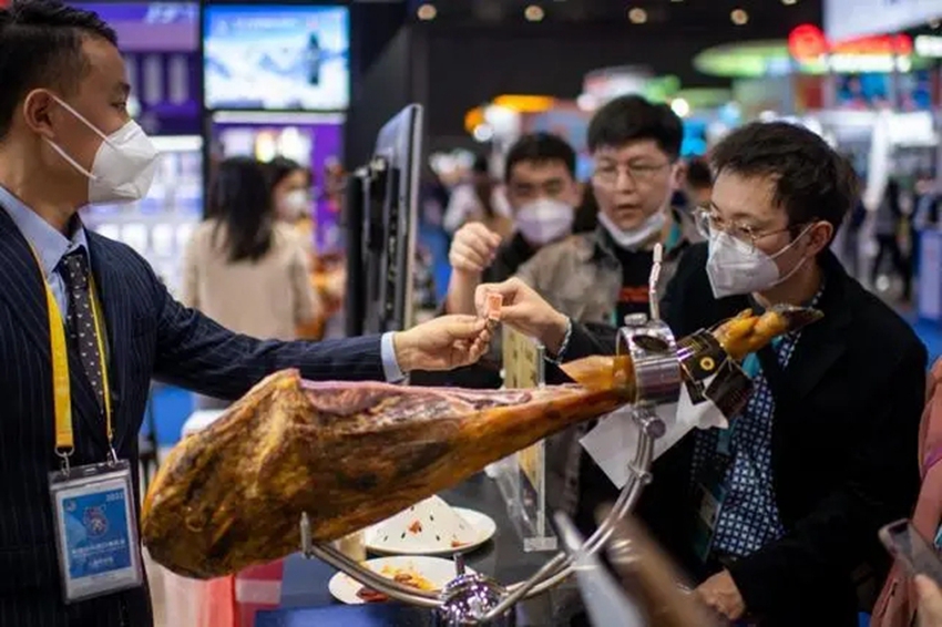 Visitors taste Spanish ham in the exhibition area for food and agricultural products during the 5th China International Import Expo (CIIE). (People's Daily Online/Weng Qiyu)