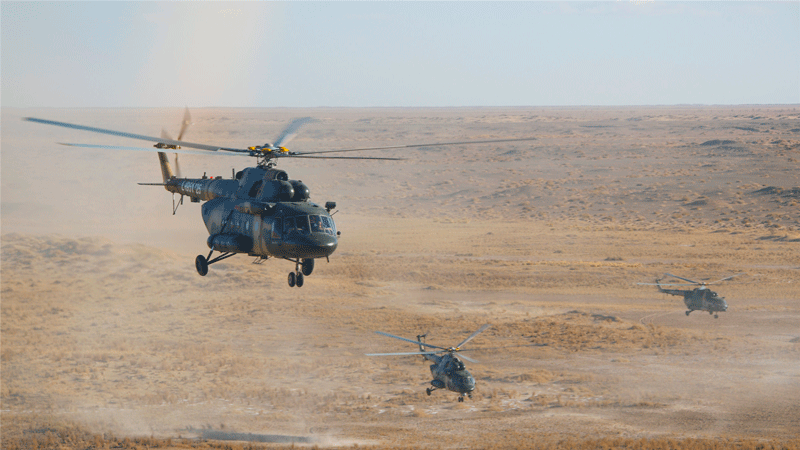 Transport helicopters kick up sand during training