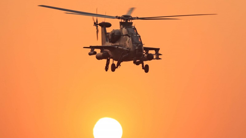 Attack helicopter flies at sunset