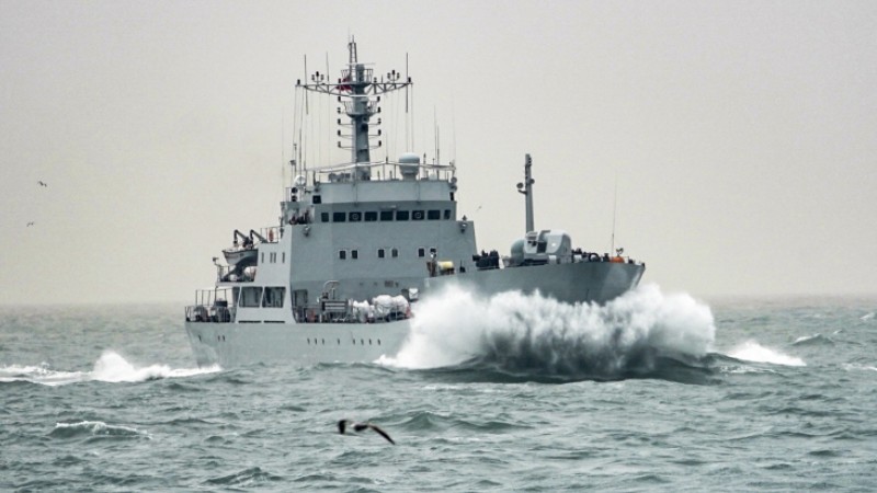 Naval vessels cleave through waves