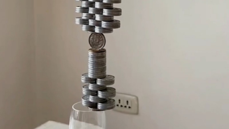 A tower of coins, balanced on the rim of a glass