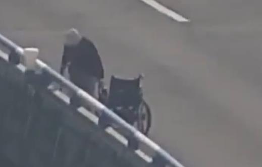 Act of kindness: Young lady aids old man in wheelchair on overpass