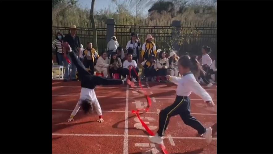 Second-grade sensation: Girl somersaults over finish line