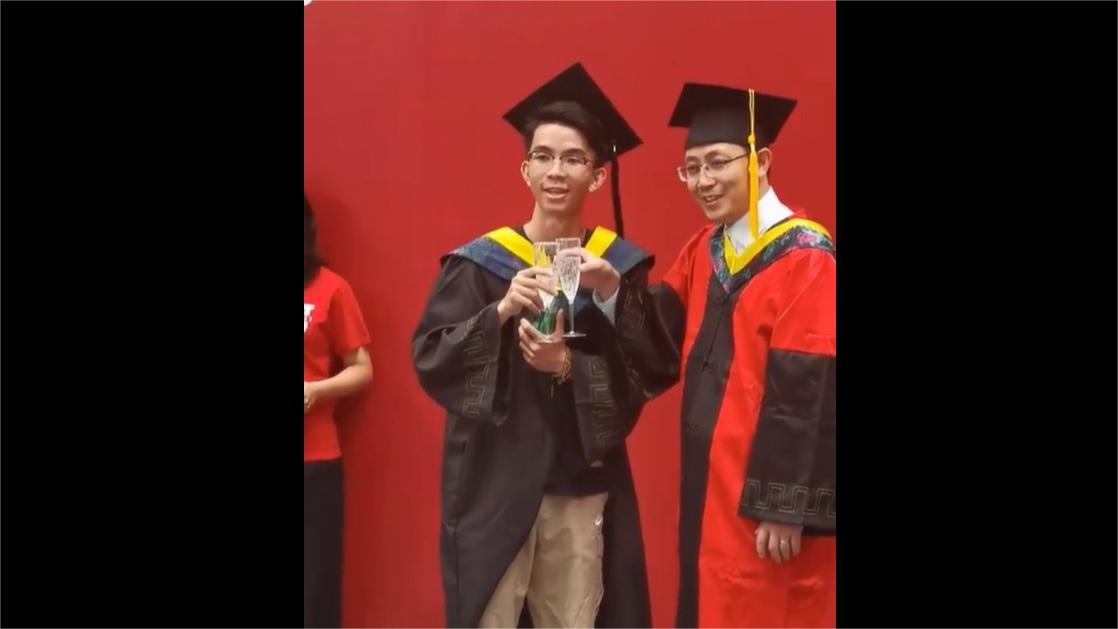 Boy toasts university graduation with champagne, joined by professor