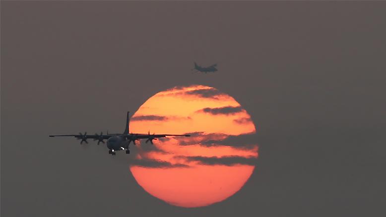 Reconnaissance aircraft fly past setting sun