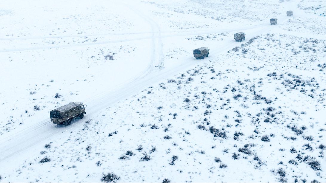 Military trucks maneuver in snowfield