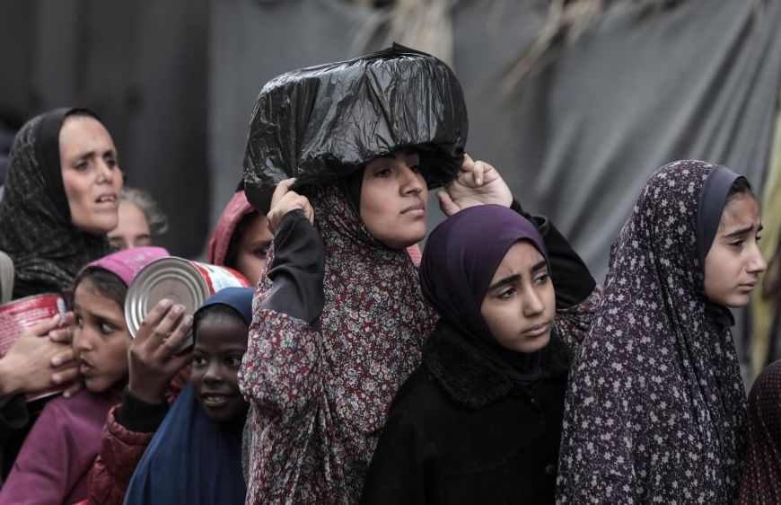 People receive food relief at food distribution center in city of Deir al-Balah, central Gaza Strip