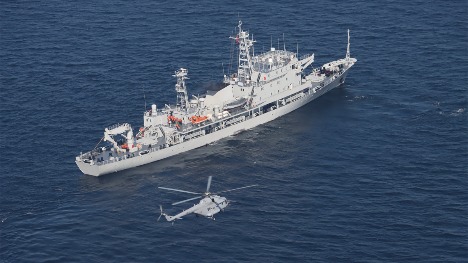 Naval ship and air force helicopter in joint search and rescue training