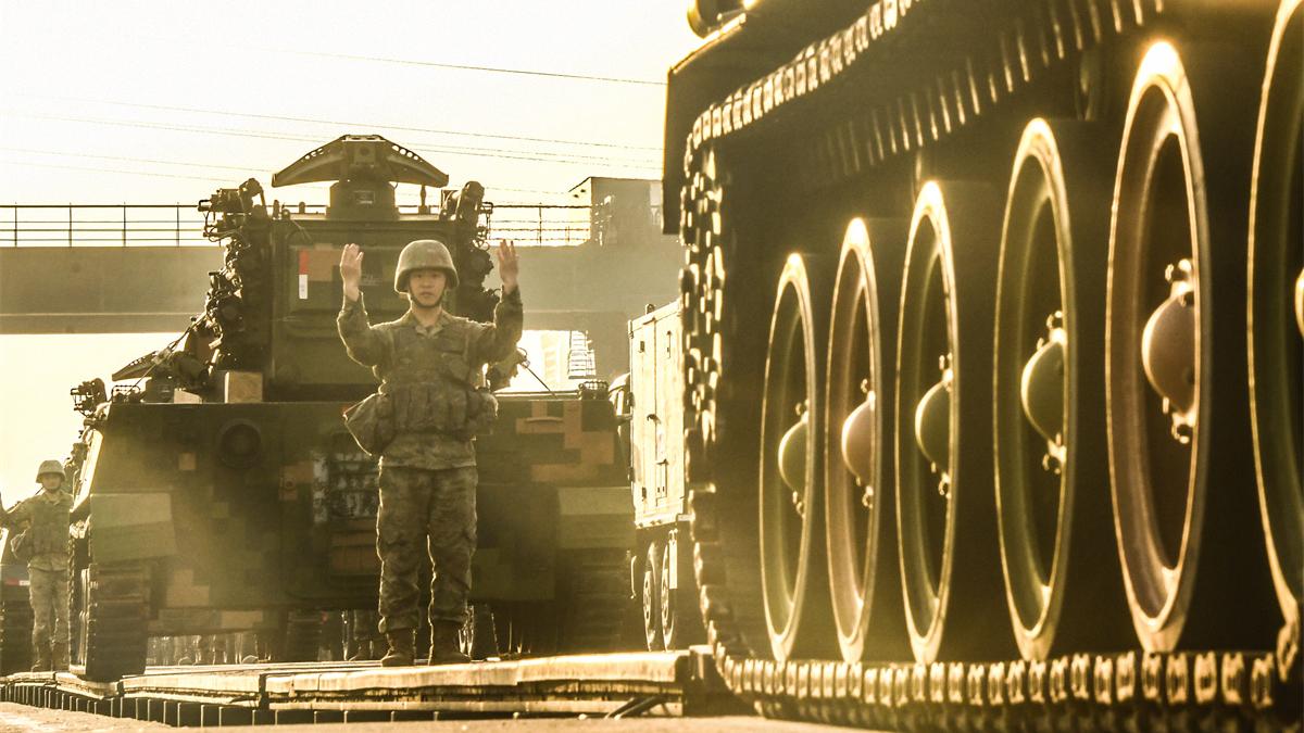 Soldiers load armored vehicles onto rail cars