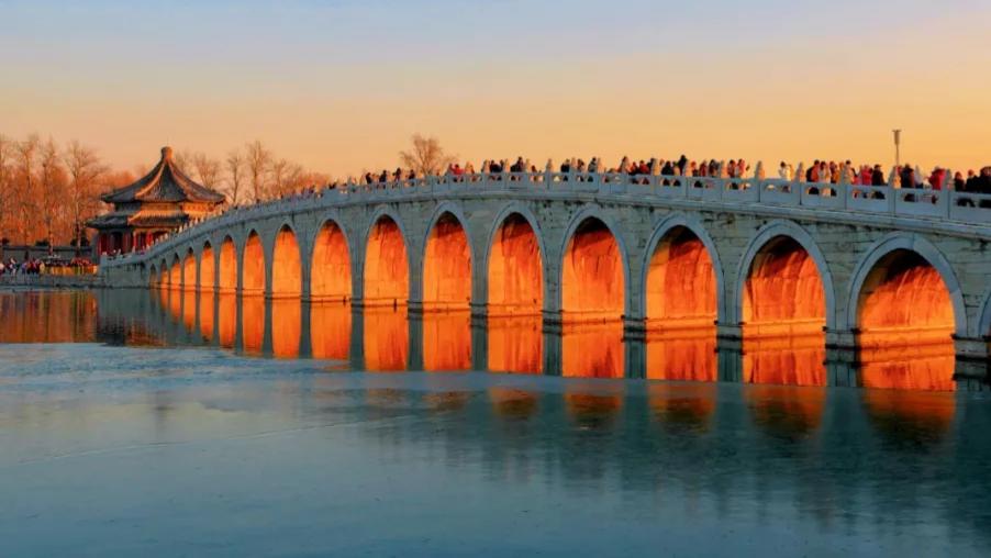 Golden sunlight streams through arches of Beijing's Seventeen-Arch Bridge