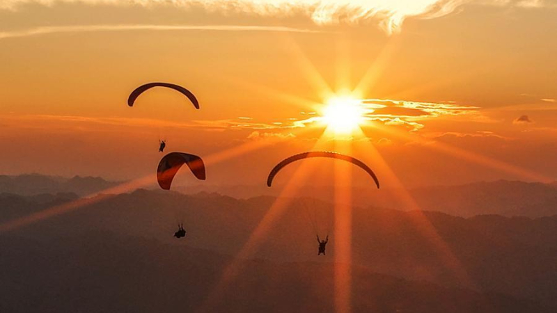 Visitors paraglide over mountains in SW China's Guizhou