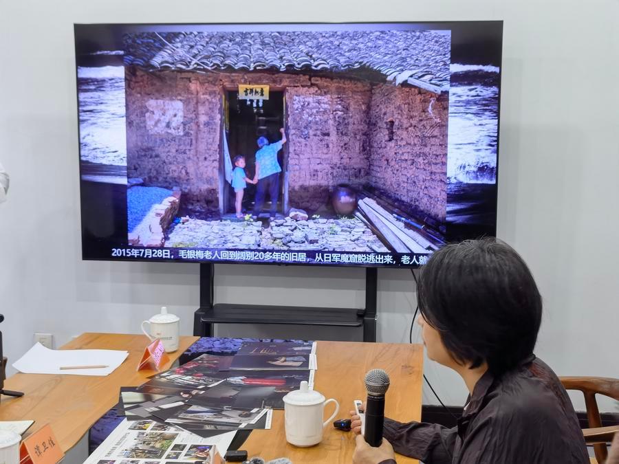 Photojournalist Yan Meihua displays a photo she took of Mao Yinmei, a Korea-born survivor of the Japanese army's World War II-era "comfort women" system, in Nanjing, capital of east China's Jiangsu Province, Aug. 14, 2026. (Xinhua/Qiu Bingqing)