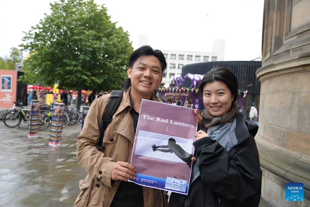 Fan Shaolun (L) and Liang Yumin, creators of Chinese-language solo play "The Red Lantern," pose for photos with a poster of their play in Edinburgh, Britain, Aug. 9, 2026. (Xinhua/Zhao Jiasong)