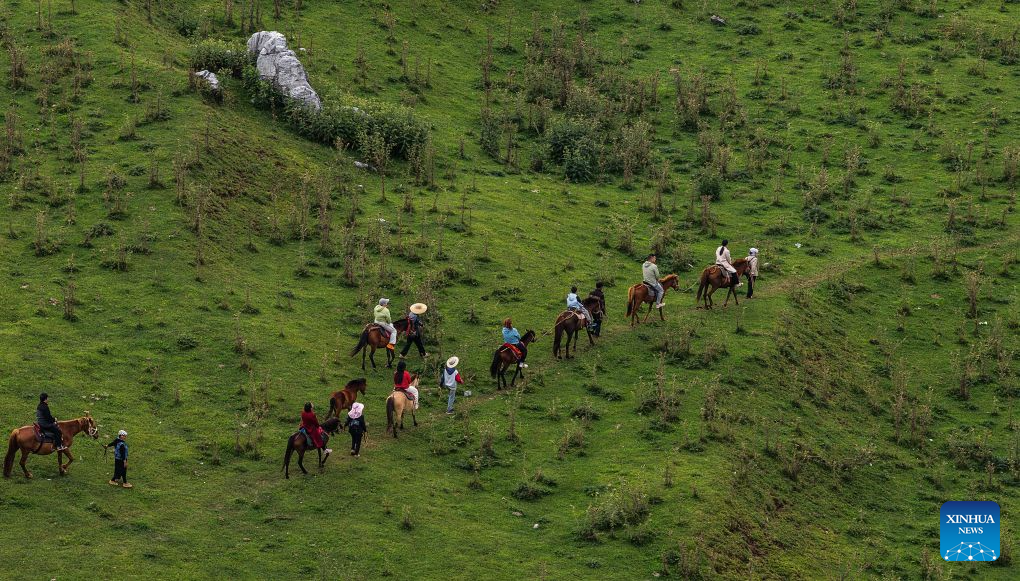 An aerial drone photo taken on Aug. 7, 2026 shows visitors riding horses in Yi-Hui-Miao Autonomous County of Weining, Bijie, southwest China's Guizhou Province. The cool climate and rich tourism resources in Guizhou have attracted lots of visitors seeking a summer retreat. (Xinhua/Tao Liang)