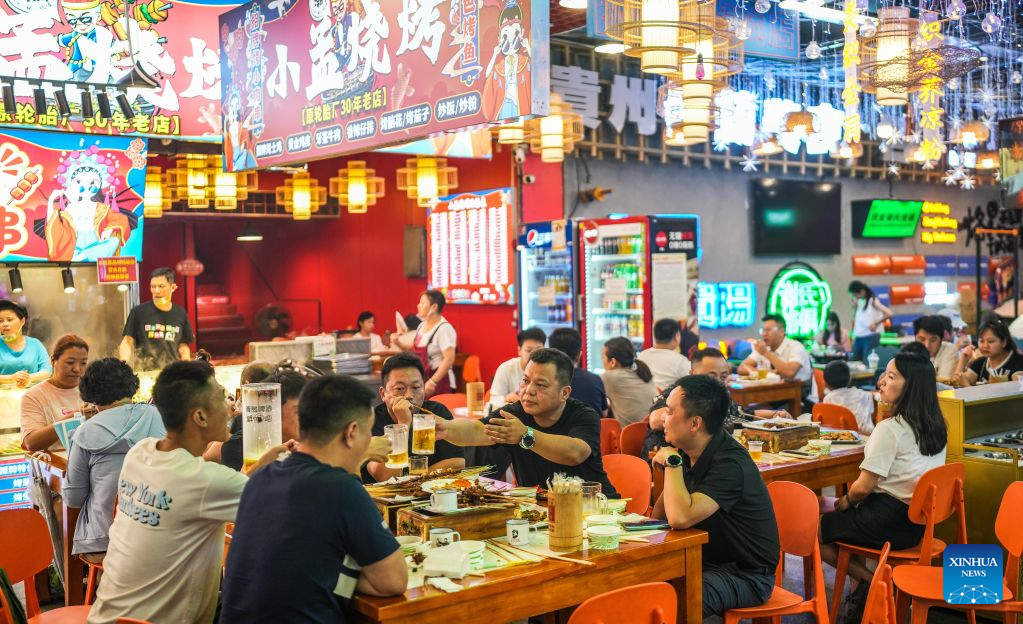 Visitors taste snacks at a market in Nanming District of Guiyang, southwest China's Guizhou Province, Aug. 14, 2026. The cool climate and rich tourism resources in Guizhou have attracted lots of visitors seeking a summer retreat. (Xinhua/Tao Liang)